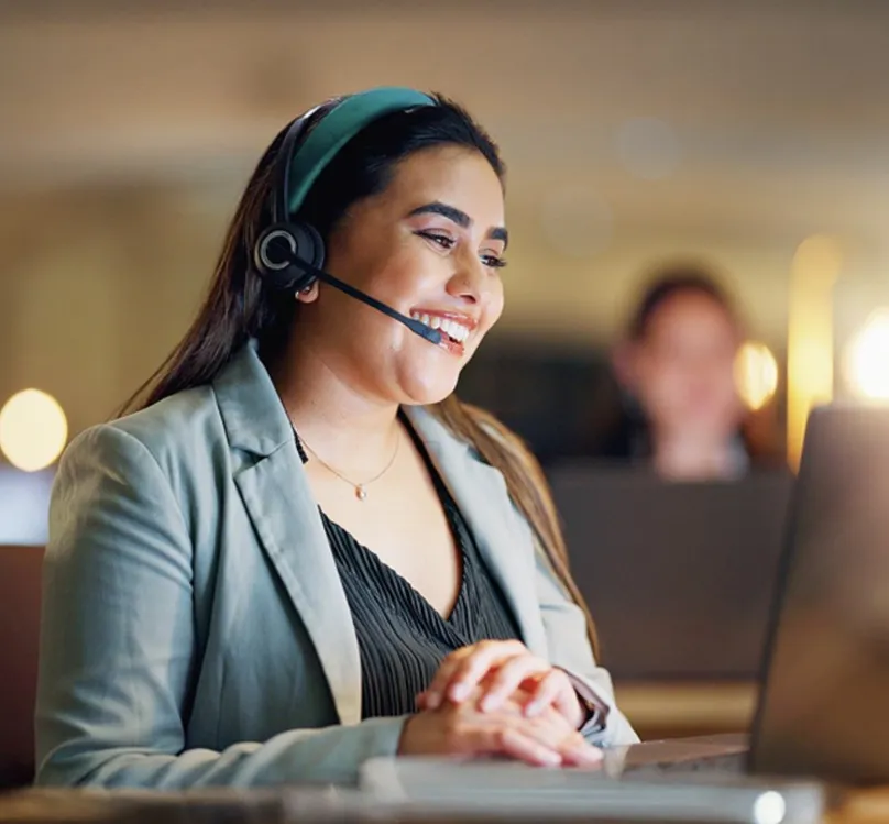 Woman smiling working on laptop with headset on